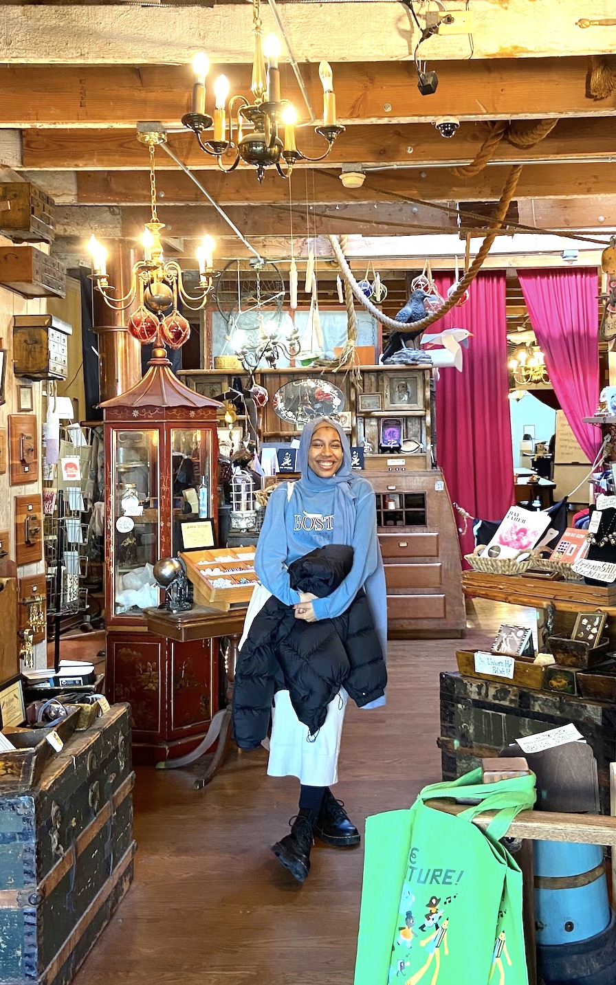 Woman in hijab standing in front of an eclectic storefront (826 Valencia, Mission Bay)